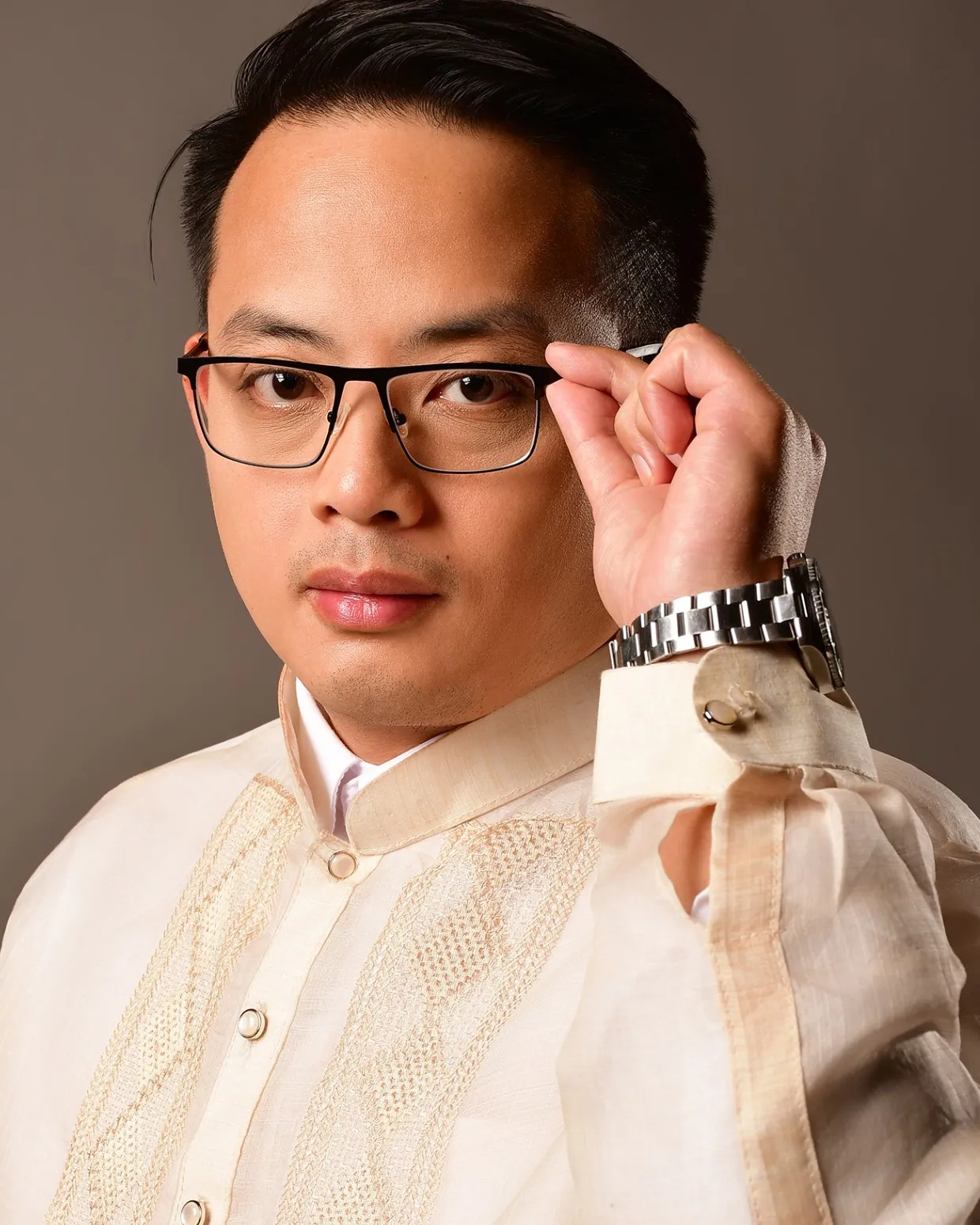 Anderson So in a barong Tagalog, adjusting his glasses